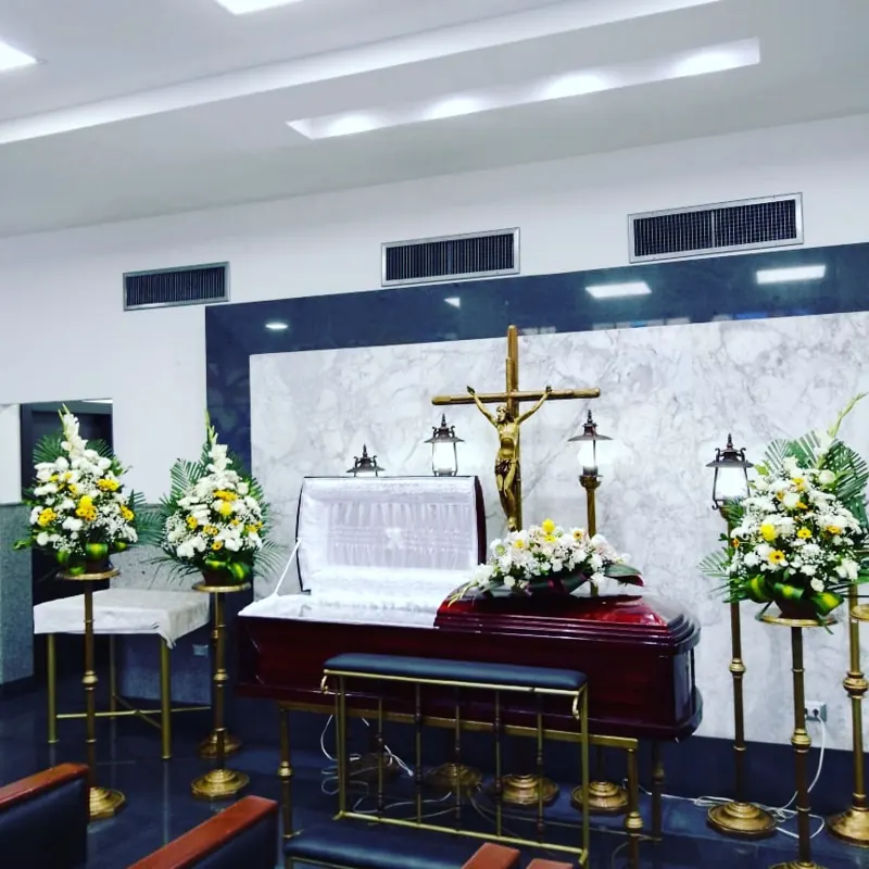 Sala velatoria con ataúd blanco y cruz dorada